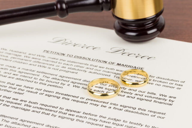 Wooden judge gavel, golden rings, and divorce decree; document