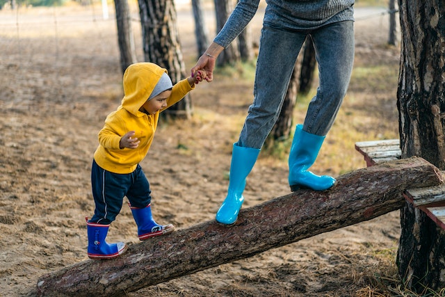 parent holding childs hand on log