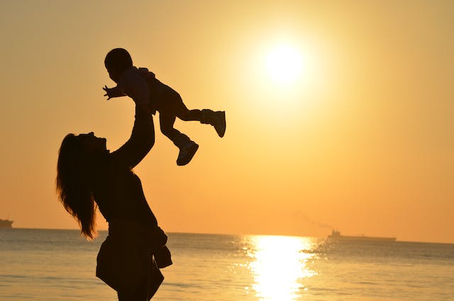 mother holding child by beach